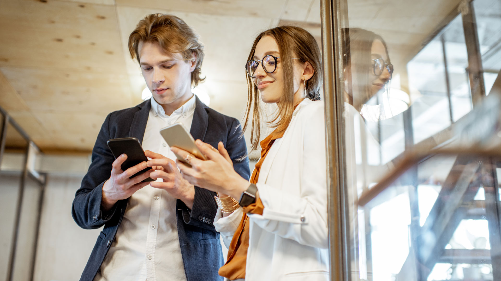 Man and woman in business clothing using their smartphones