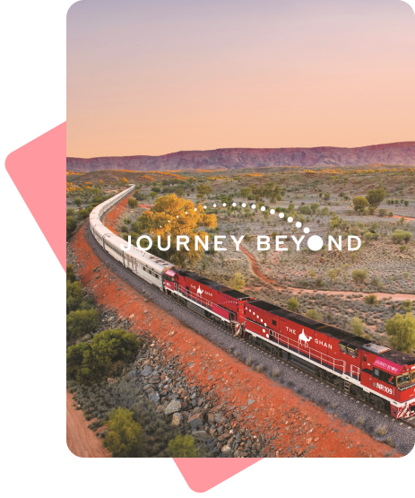 Photograph of a long red and white train, snaking it's way through the Australian outback. Overlayed on the photo is the logo for "Journey Beyond".