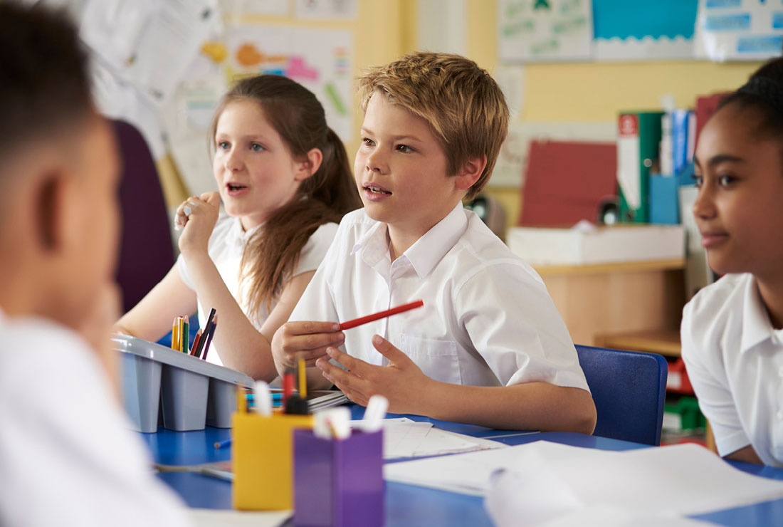 NSW Department of Education Assistant School Travel Program case study - Photo of a classroom of children sat at their desks with pens and pencils in hand.