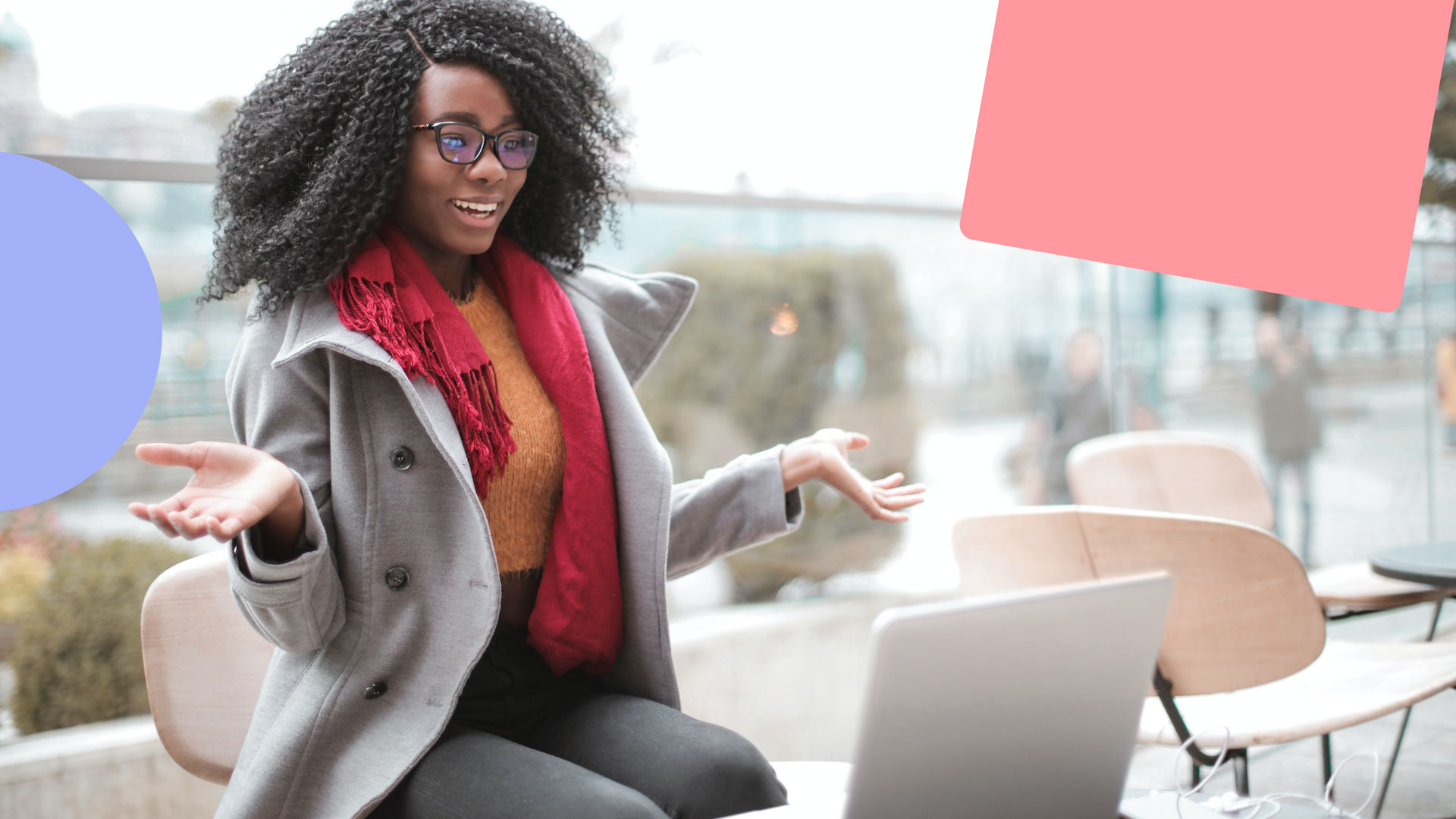 A cheerful woman wearing a scarf and coat is sitting outside. In front of her is an open laptop. She is looking surprised because of how good the personalised website experience is.