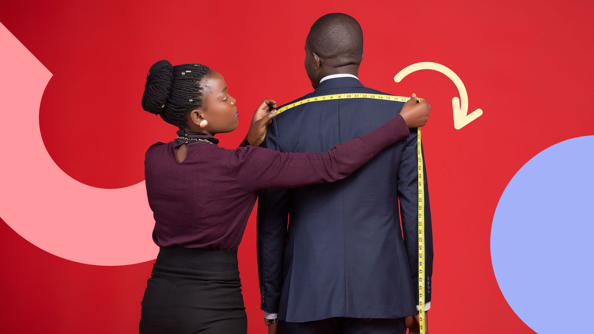 A woman seamstress measuring the width of a man's shoulders in order to personalise the fit of his suit.