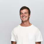 Paddy Morgan, Website Specialist, Sydney Opera House, wearing w white t-shirt and smiling at the camera.