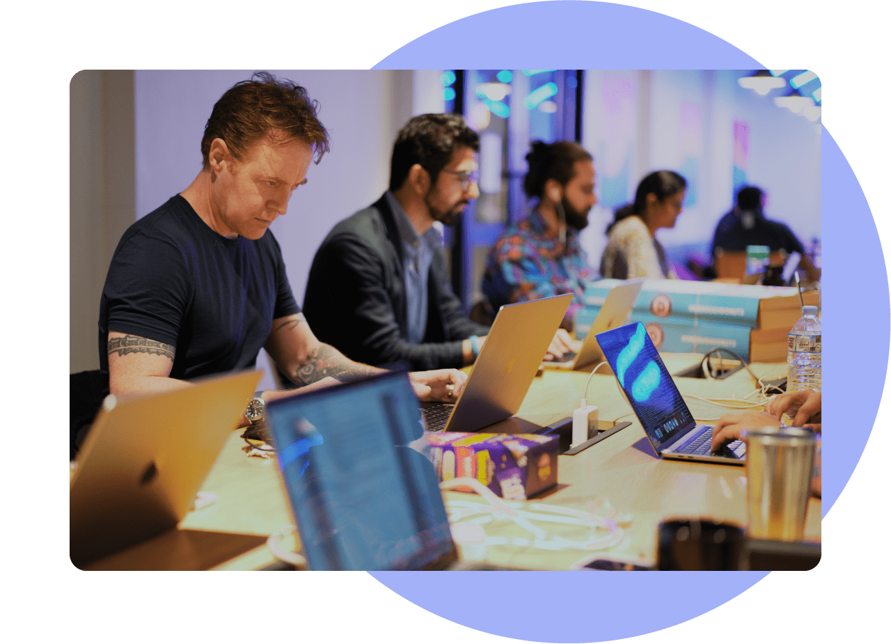 Service - Technical Development. A group of men and women sat along a table working hard with their laptops.