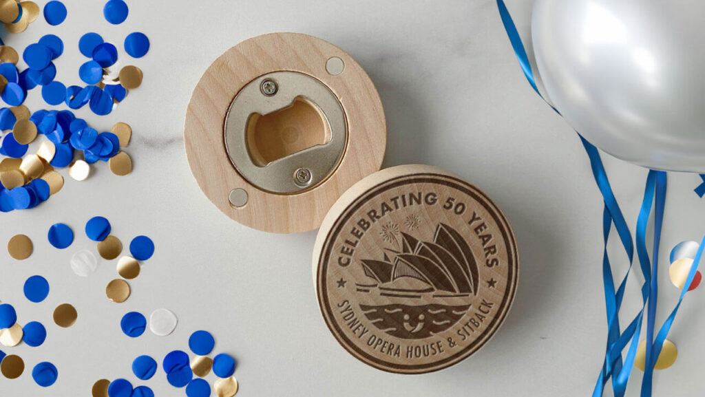 A wooden bottle opener with the words "Celebrating 50 years - Sydney Opera House and Sitback"