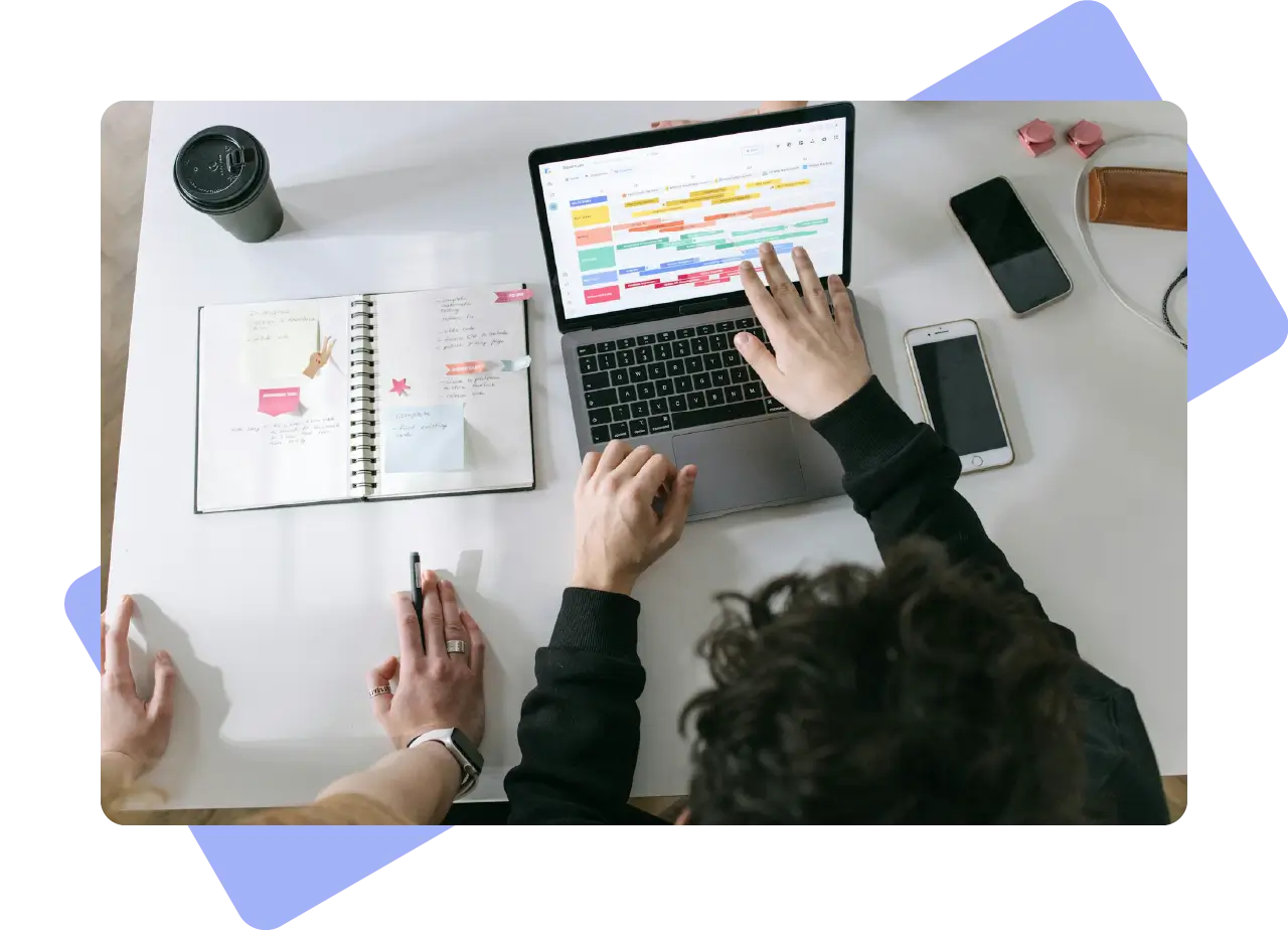 Overhead view of a content calendar and Gantt chart on a laptop, surrounded by notebooks and planning tools.