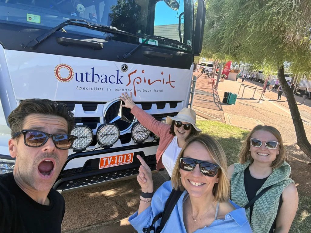 Sitback and Journey Beyond smiling and pulling silly poses in front of an Outback Spirit Tours bus